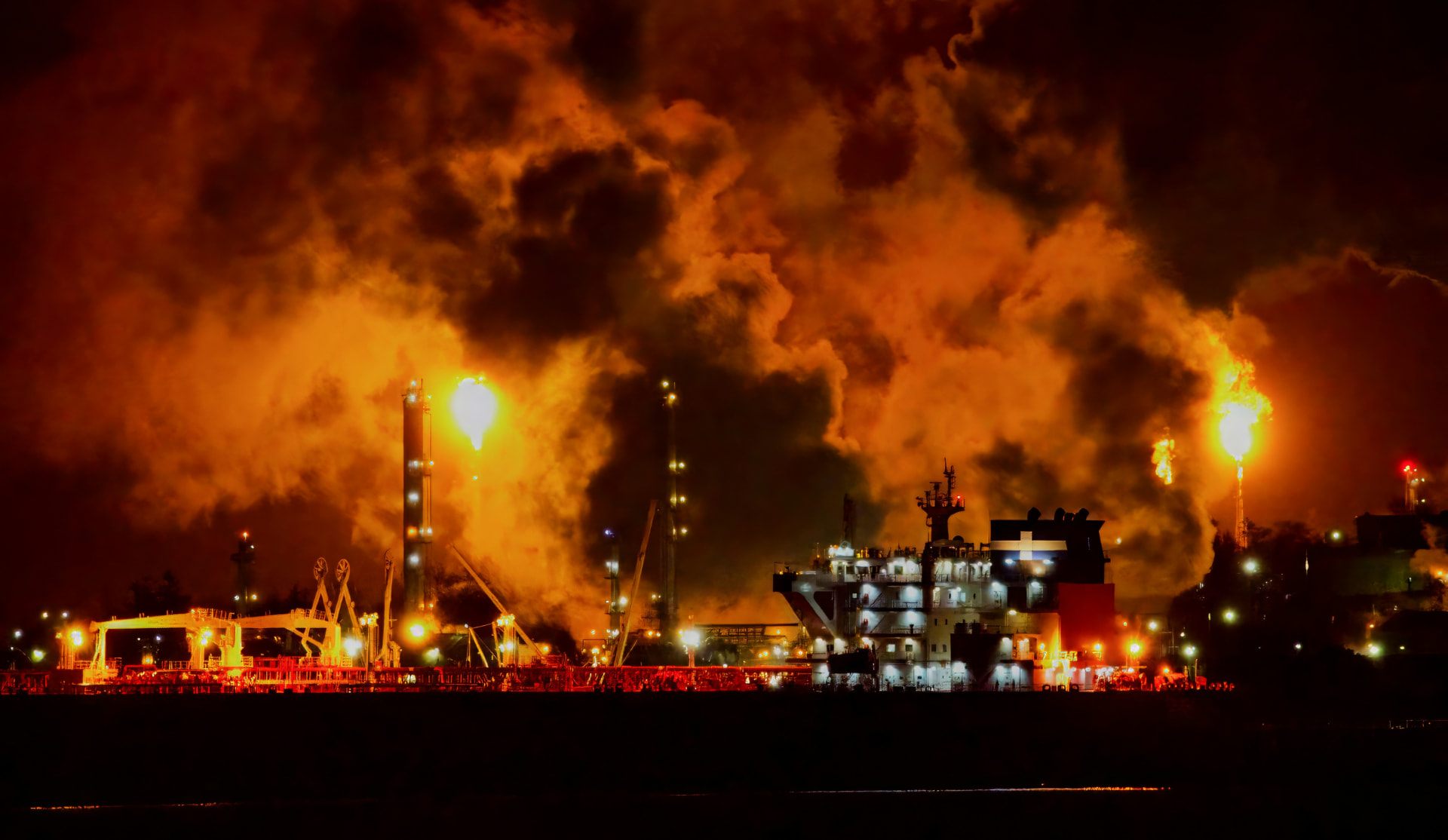 Refinery flare stacks burning heavy fuel oil at night