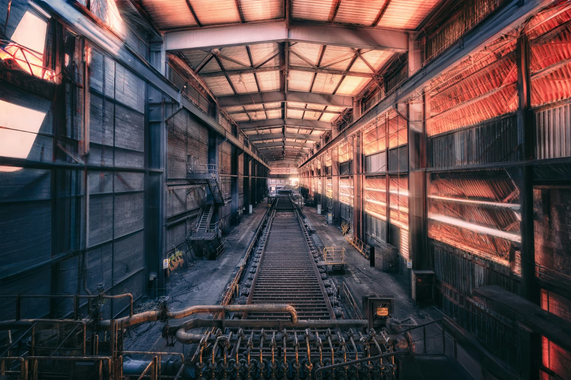 Industrial plant hall with conveyor rails at sunset